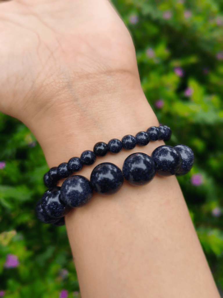 Blue Sandstone round-bead bracelets worn together on a wrist outdoors.
