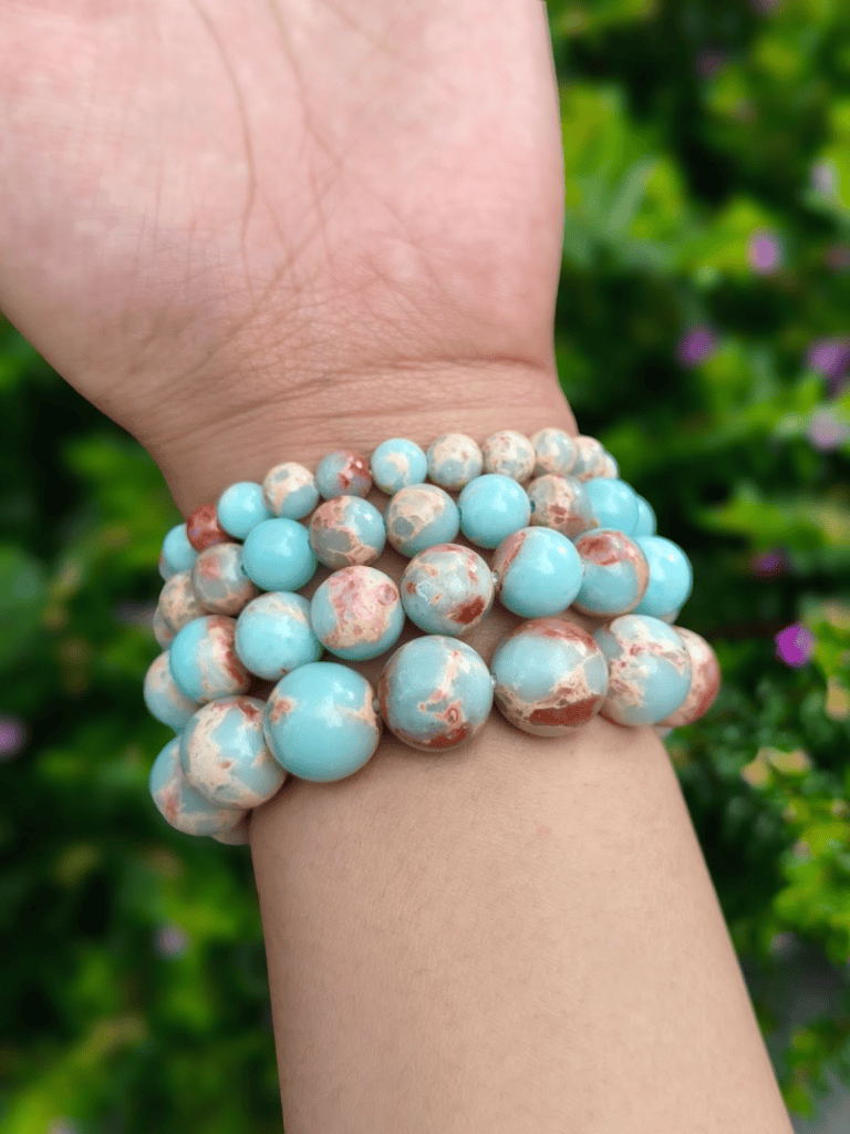 Blue Snakeskin Jasper round-bead bracelets worn together on a wrist outdoors.