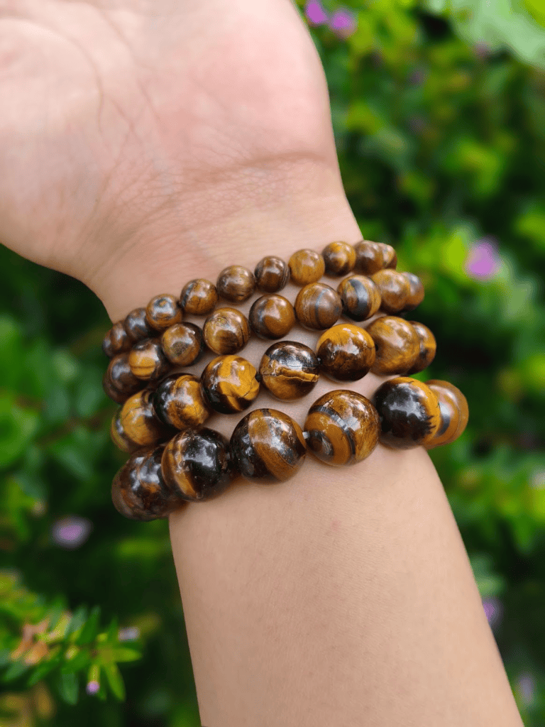 Brown Tiger's Eye round-bead bracelets worn together on a wrist outdoors.