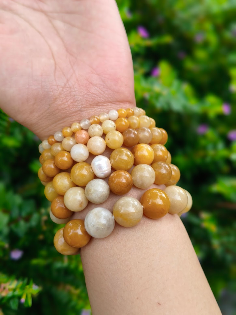 Butter Quartz round-bead bracelets worn together on a wrist outdoors.