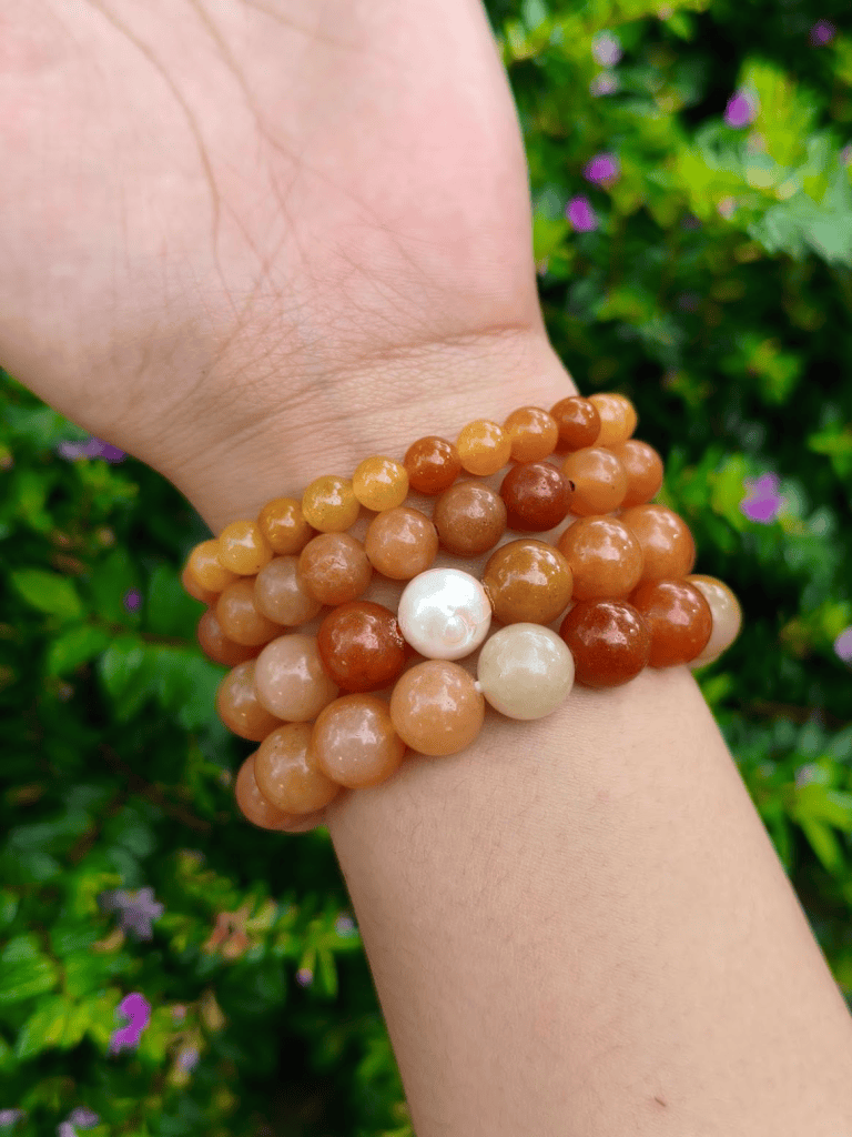 Carnelian round-bead bracelets worn together on a wrist outdoors.