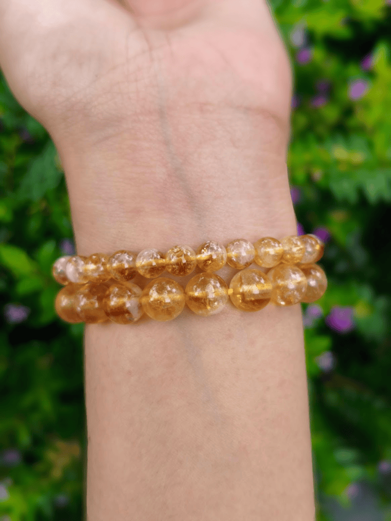 Citrine round-bead bracelets worn together on a wrist outdoors.