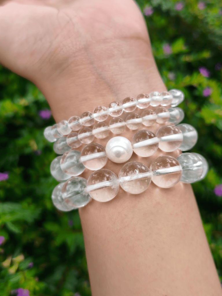 Clear Quartz round-bead bracelets worn together on a wrist outdoors.