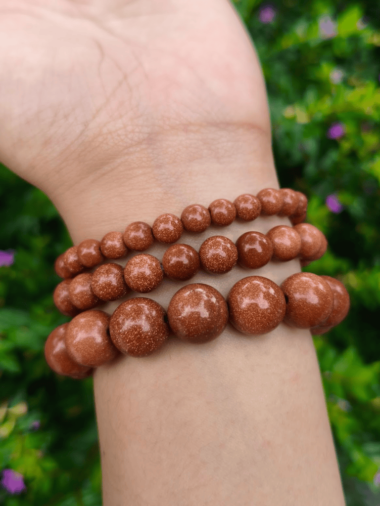 Golden Sandstone round-bead bracelets worn together on a wrist outdoors.