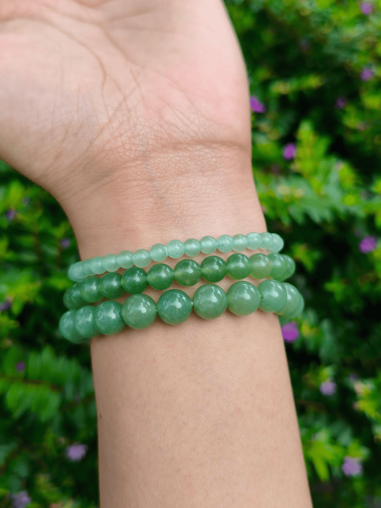 Green Aventurine round-bead bracelets worn together on a wrist outdoors.