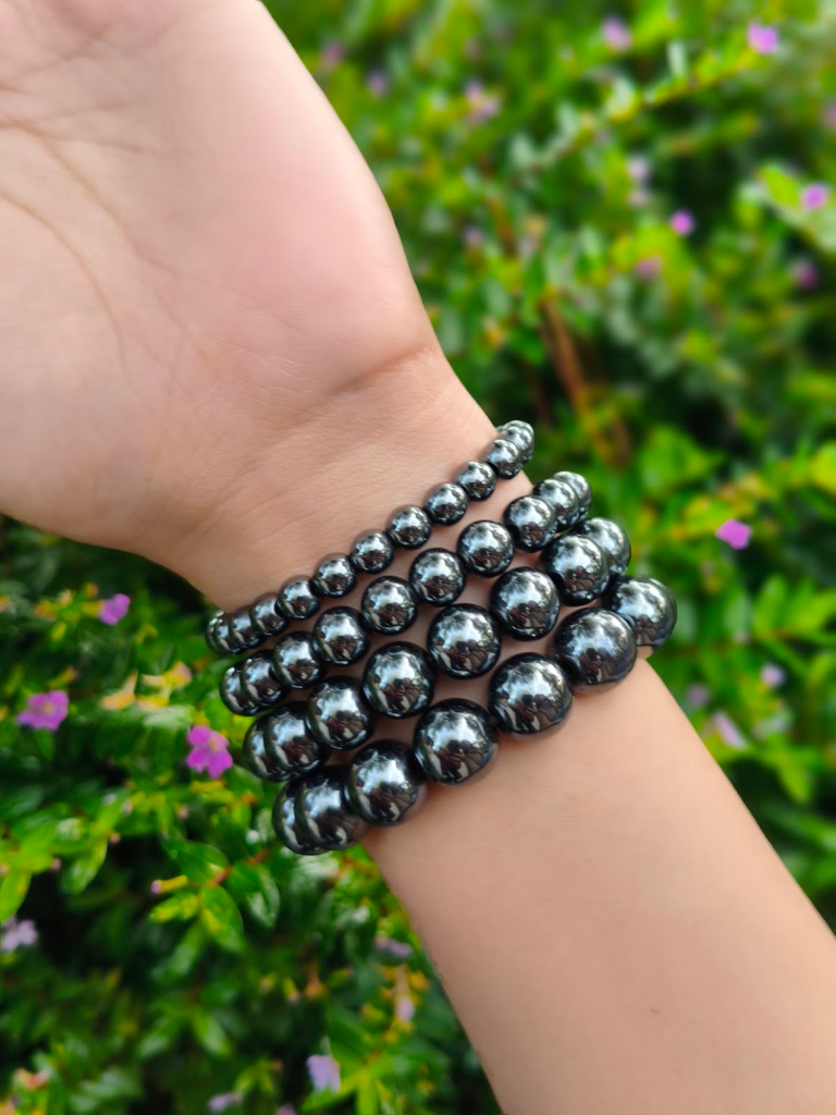 Hematite round-bead bracelets worn together on a wrist outdoors.