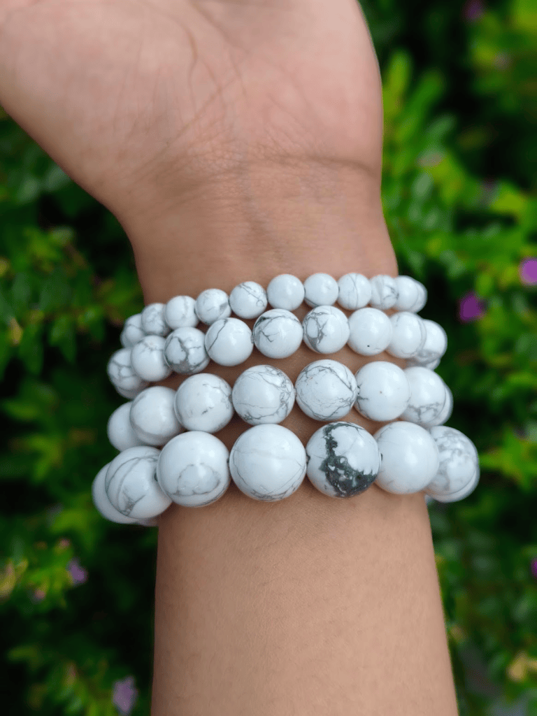 Howlite round-bead bracelets worn together on a wrist outdoors.