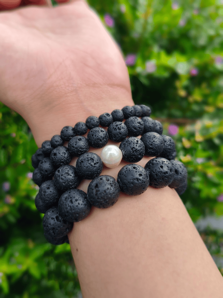 Lava Rock round-bead bracelets worn together on a wrist outdoors.