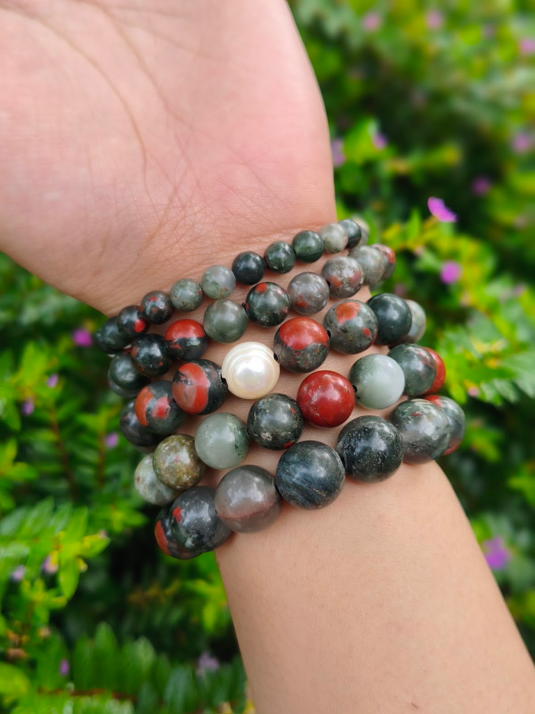 Light Bloodstone round-bead bracelets worn together on a wrist outdoors.