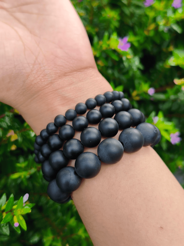 Matte Onyx round-bead bracelets worn together on a wrist outdoors.