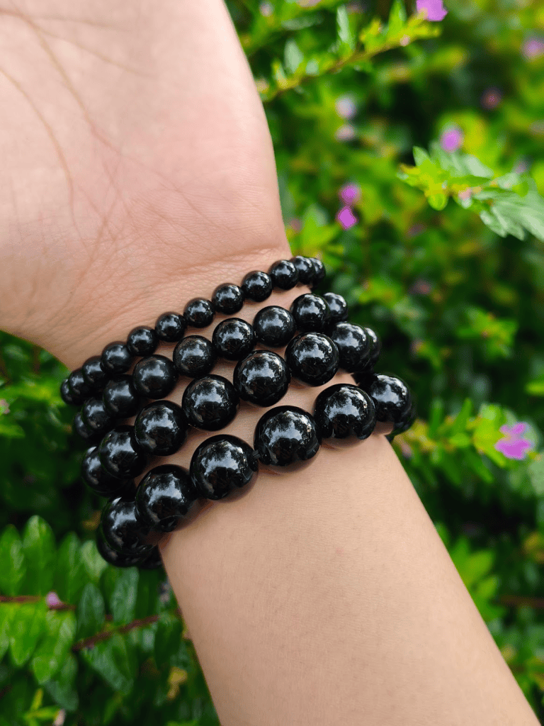 Onyx round-bead bracelets worn together on a wrist outdoors.