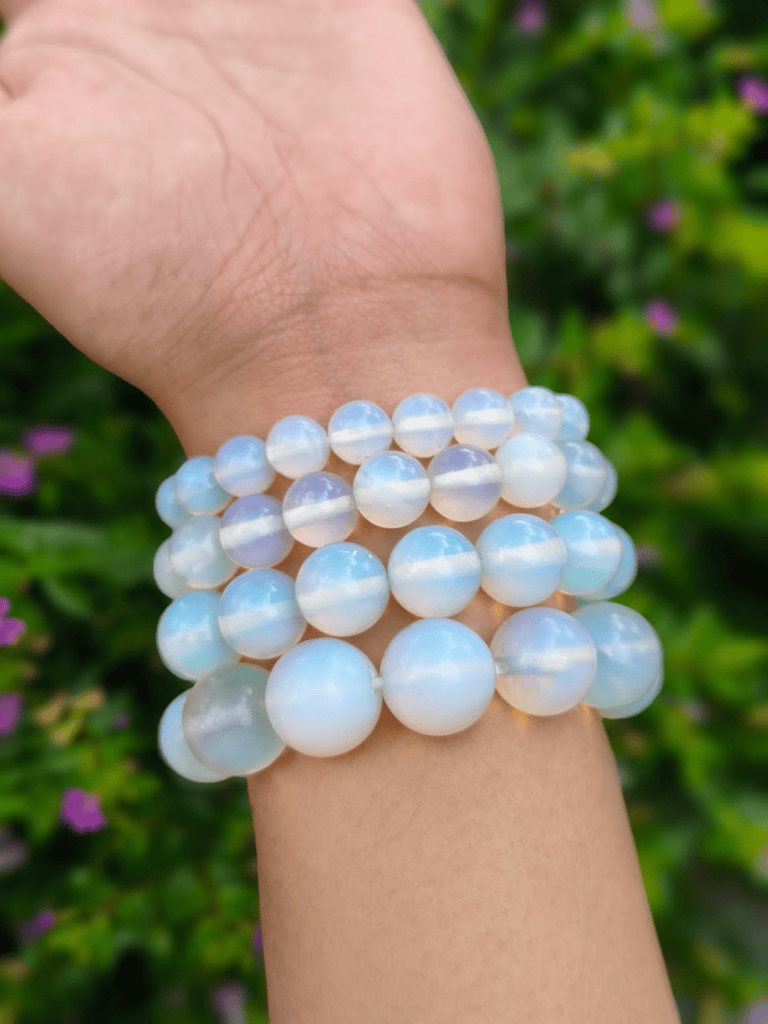 Opalite round-bead bracelets worn together on a wrist outdoors.