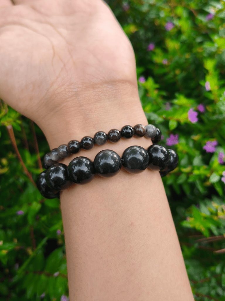 Silver Sheen Obsidian round-bead bracelets worn together on a wrist outdoors.