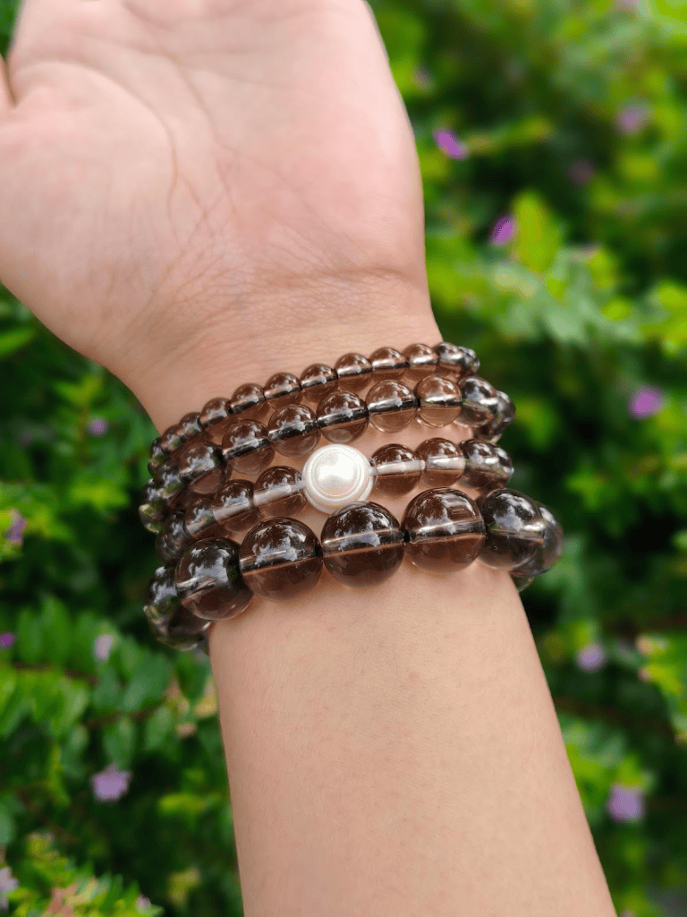 Smokey Quartz round-bead bracelets worn together on a wrist outdoors.