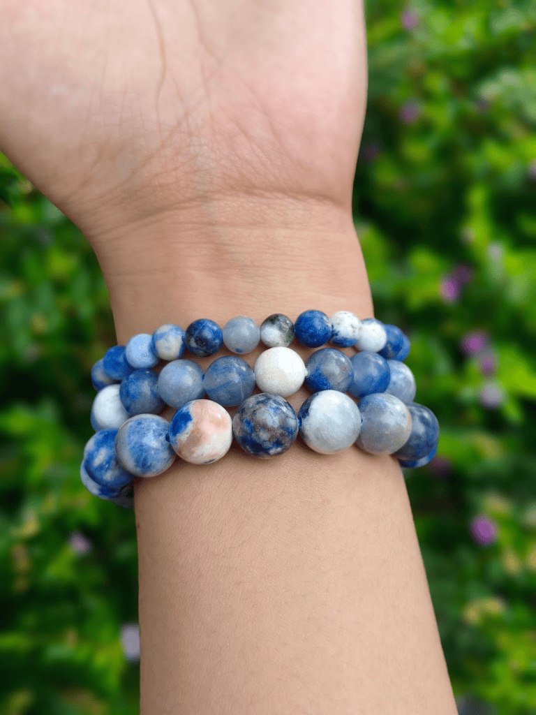 Sodalite round-bead bracelets worn together on a wrist outdoors.