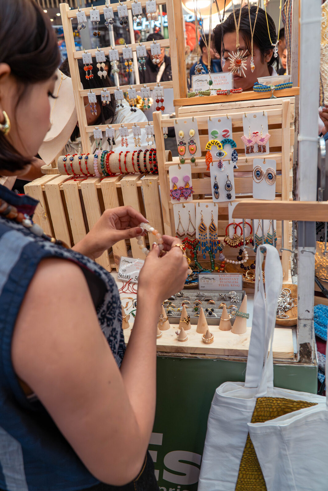 A customer browsing TÁWID jewelry at a market display.